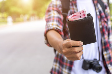 Hand of Asian tourist giving banknote and black wallet that he found in tourist attraction.