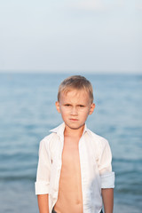 Fototapeta na wymiar Portrait with little boy standing on the beach with blurry background by the sea
