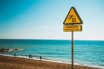 Yellow sign banner indicating a submerged pipe dangerous zone. Danger submerged pipe warning sign.