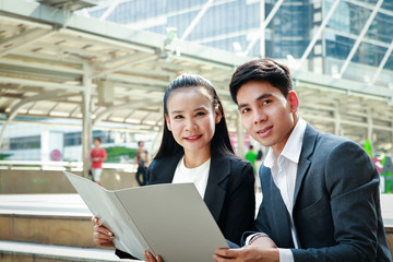 Male and female office workers sit outdoors and talk about planning.