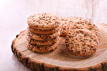 Cookies of sesame seeds, sunflower seeds and other spices on a wooden plate. Bright key