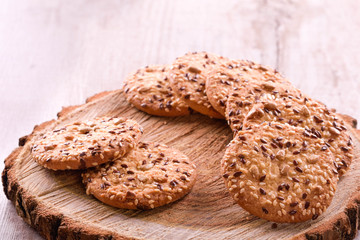 Cookies of sesame seeds, sunflower seeds and other spices on a wooden plate. Bright key