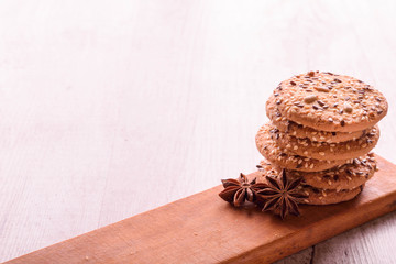 Fototapeta premium Cookies of sesame seeds, sunflower seeds and other spices on a wooden plate. Bright key
