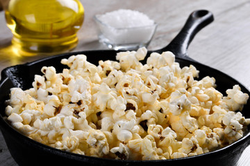  Prepared popcorn in frying pan, corn seeds in bowl and corncobs on kitchen table.Air salty popcorn. Salt popcorn on the wooden background . Chees .Popcorn texture