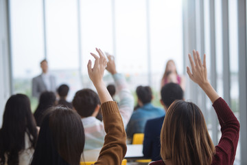 Raised up hands and arms of large group in seminar class room to agree with speaker at conference seminar meeting room - obrazy, fototapety, plakaty