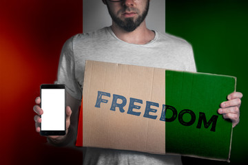 Concept of freedoms and human rights. A man with a cardboard and a phone in his hand. The Flag of...