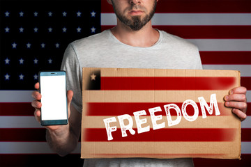 Concept of freedoms and human rights. A man with a cardboard and a phone in his hand. The Flag of...