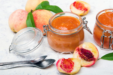 Homemade peach jam with organic fruit. Sweet preserves on a light background