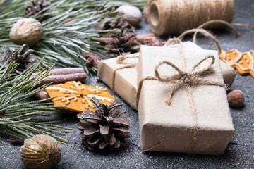 Christmas presents, gingerbreads, pine twigs and cones covered with snow on dark background