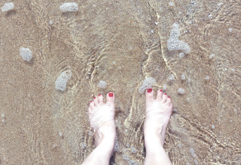 woman's feet standing in a beach wave