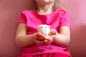 Fototapeta na wymiar Little hands holding pink piggy bank.