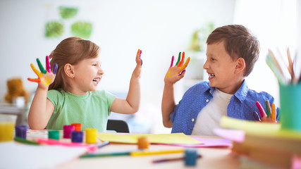 funny kids show their palms the painted paint. creative classes fine arts. two children a boy and a girl laugh. selective focusing on the palm.