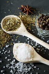 Wooden spoon with Italian seasoning-dried oregano with thyme,vegetables.Oregano in a wooden spoon on a rocky concrete dark black background with a place for text Top view
