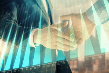 Double exposure of financial graph on cityscape background with two businessman handshake. Concept of stock market deal