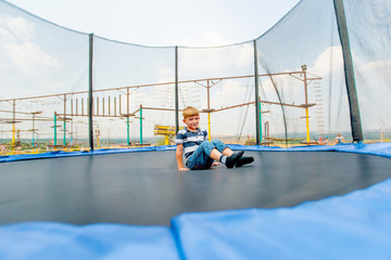 The boy jumps on a trampoline in an amusement park, performing various stunts.