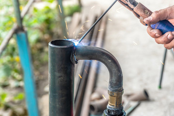 Worker cooks the heating pipe, welding joint. Preparing for winter heating.