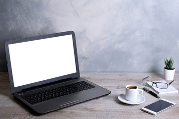 Laptop with blank screen for graphic display montage .Computer on wooden gray desk in office room. Mock up with plastic  plant