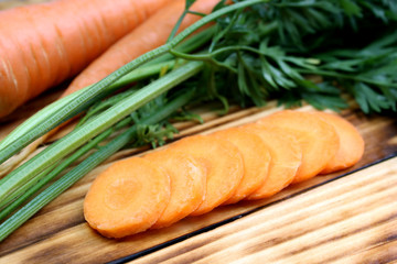 Fresh crop of carrots with tops and sliced in circles lies on the table