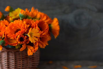 bouquet of medicinal herbs calendula in a basket on a wooden background with a copy of space
