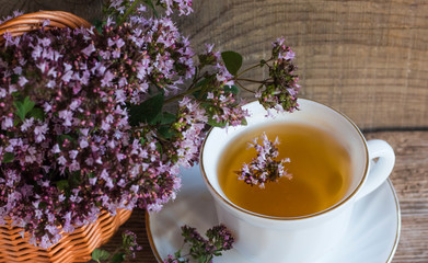 a Cup of hot aromatic tea with oregano herbs on a wooden background