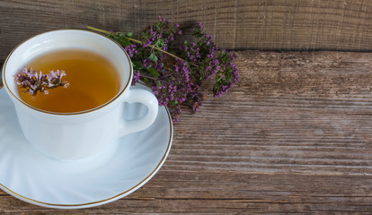 a Cup of hot aromatic tea with herb oregano on a wooden background with a copy of space