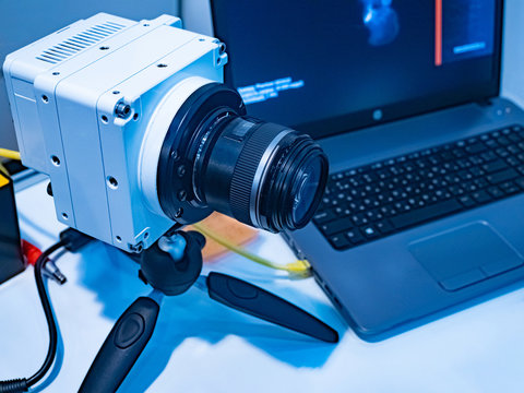The camera on the tripod and the computer on the desktop of the engineer. High-speed video camera. High-speed video. Camera to shoot super fast events.