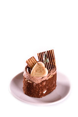  A biscuit cake is sprinkled with cocoa with chocolate cream, a heart of white chocolate, a slice of chocolate tile  and a delicious waffle on wooden background.