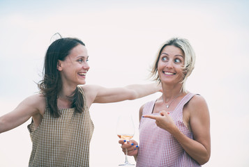 Two young attractive women resting and drinking white summer wine