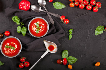 Traditional spanish cold tomato soup gazpacho in a bowl over black stone background.