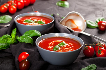 Traditional spanish cold tomato soup gazpacho in a bowl over black stone background.