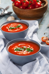 Traditional spanish cold tomato soup gazpacho in a bowl over blue wooden background.