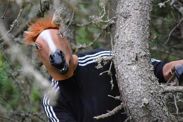 Hombre con cabeza de caballo escondido en el bosque, acechando.