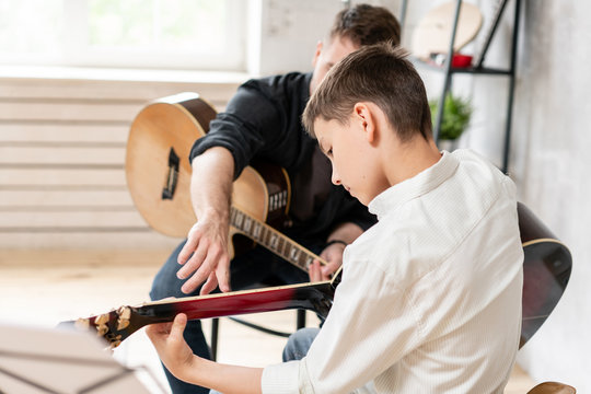 A personal tutor explains to his young student how to play studied chord correctly. Musical education at home