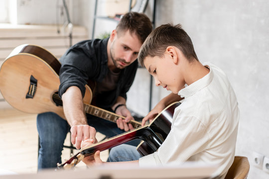 Adult Man Explains His Son, Who Learn To Play Guitar, How To Play Studied Chord Correctly. Education With Family