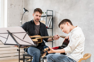 Two brothers of different ages rehearsing a melody from a sheet music