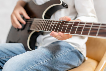 Closeup of electric guitar in hands of young boy in casual clothes