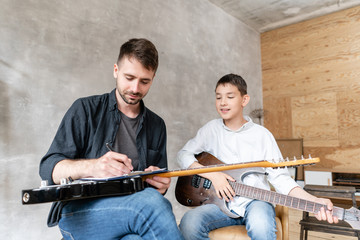 Older brother explains to his younger one how to use notes on music sheets on an exapmple