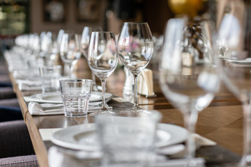 Wine glasses in the foreground. Wedding Banquet or gala dinner. The chairs and table for guests, served with cutlery and crockery.