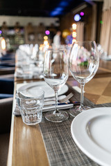 Wine glasses in the foreground. Wedding Banquet or gala dinner. The chairs and table for guests, served with cutlery and crockery.