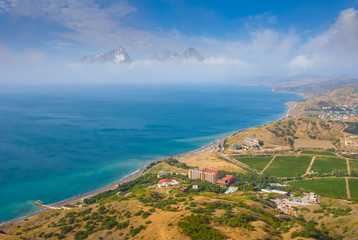 Obraz premium emerald sea bay with small town on the beach with rocky mountain beyond