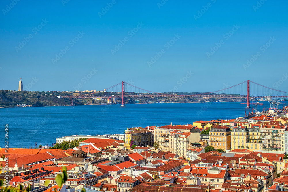 Wall mural views of lisboa where you can see the roofs of their houses, tajo river, april 25 bridge and cristo 