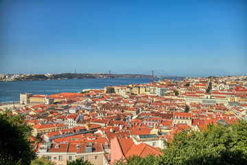 Fototapeta na wymiar Views of Lisboa where you can see the roofs of their houses, Tajo River, April 25 bridge and Cristo Rey