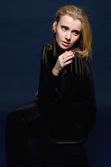 beautiful woman in black velvet costume sitting on high chair.