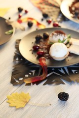 Halloween treat, autumn leaves and dessert with chocolate, ice cream and jelly worms on a wooden table