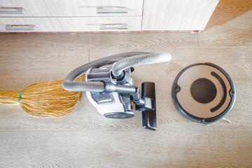 Robot vacuum cleaner with evil eyes and grin and regular vacuum cleaners side by side. Old versus...