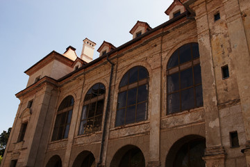 Obraz premium Old European palace building with wall murals and big arched windows on blue sky background