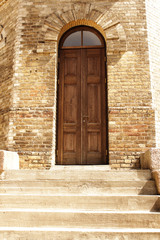 Wooden arch door in yellow brick water tower wall on sunny day