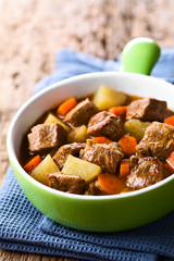 Fresh homemade beef stew with carrot and potatoes served in green bowl (Selective Focus, Focus one...