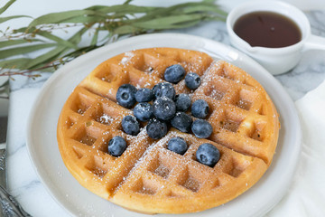 Belgian Waffle with Blueberries and Maple Syrup, Dusted with Powdered Sugar, Flay Lay on Marble Background, Copy Space
