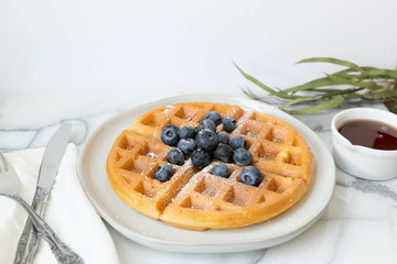 Belgian Waffle with Blueberries and Maple Syrup, Dusted with Powdered Sugar, Flay Lay on Marble Background, Copy Space